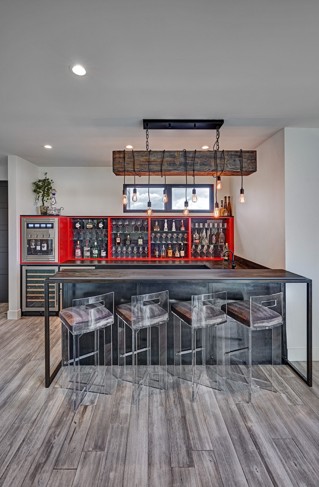 Imagen de bar en casa con barra de bar en U industrial grande con puertas de armario rojas, suelo marrón y encimeras grises