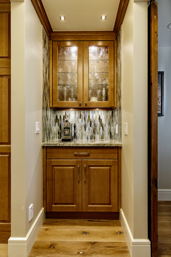 Klassisk inredning av en liten parallell hemmabar med vask, med luckor med upphöjd panel, skåp i mellenmörkt trä, granitbänkskiva, flerfärgad stänkskydd, stänkskydd i glaskakel och ljust trägolv
