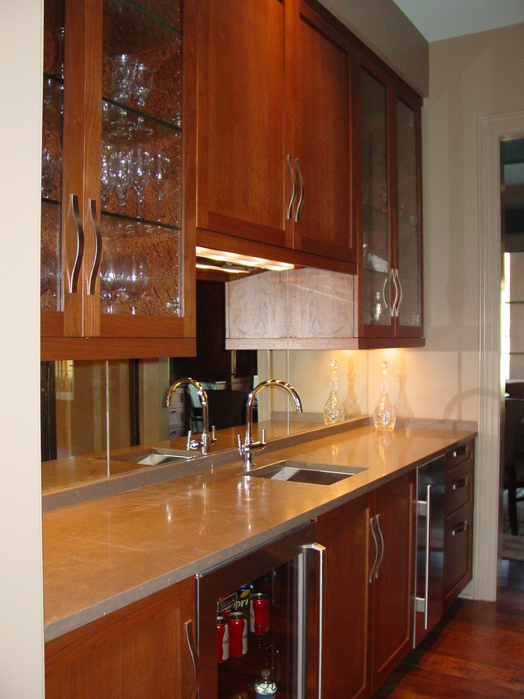 Modern inredning av en mellanstor linjär hemmabar med vask, med en undermonterad diskho, skåp i shakerstil, skåp i mellenmörkt trä, bänkskiva i koppar, spegel som stänkskydd och mörkt trägolv