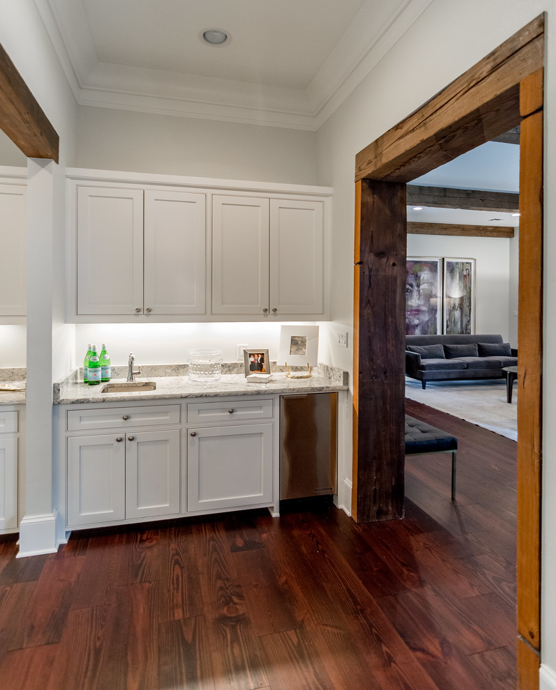 Medium sized classic wet bar in New Orleans with a submerged sink, recessed-panel cabinets, white cabinets, marble worktops and dark hardwood flooring.