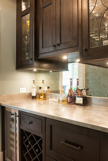 This is an example of a medium sized classic single-wall wet bar in New York with beaded cabinets, dark wood cabinets, concrete worktops and mirror splashback.