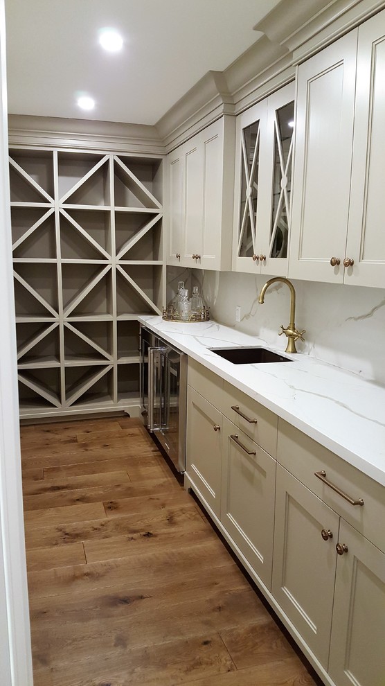 Medium sized classic l-shaped wet bar in Toronto with a submerged sink, recessed-panel cabinets, white cabinets, marble worktops, white splashback, medium hardwood flooring and marble splashback.