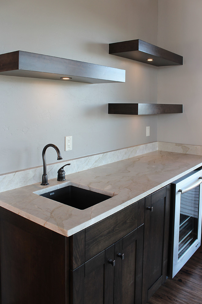 Photo of a large contemporary single-wall wet bar in Albuquerque with a submerged sink, shaker cabinets, dark wood cabinets, engineered stone countertops, medium hardwood flooring, brown floors and beige worktops.