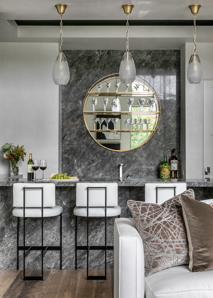 Cette photo montre un bar de salon parallèle tendance avec des tabourets, une crédence grise, une crédence en dalle de pierre, parquet foncé, un sol marron et un plan de travail gris.