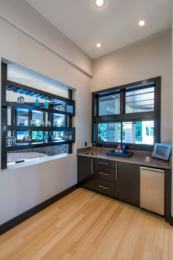 Photo of a medium sized modern single-wall wet bar in Other with flat-panel cabinets, black cabinets, engineered stone countertops and bamboo flooring.