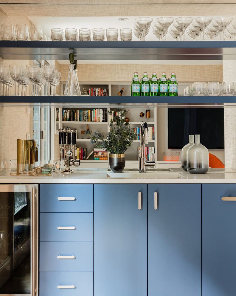 Immagine di un angolo bar con lavandino minimalista di medie dimensioni con lavello sottopiano, ante lisce, ante blu, top in granito, paraspruzzi a specchio e pavimento in legno massello medio