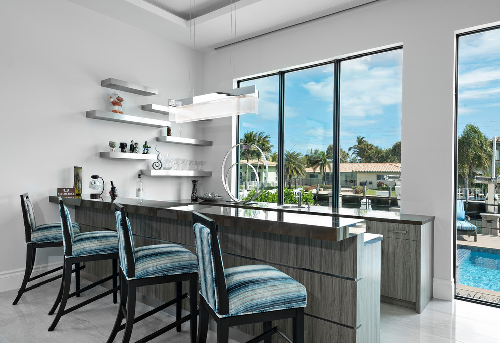 マイアミにあるコンテンポラリースタイルのおしゃれな着席型バー (フラットパネル扉のキャビネット、グレーのキッチンカウンター、グレーの床) の写真
