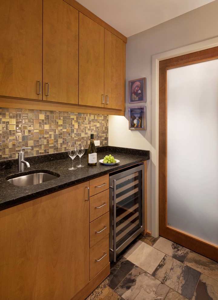 Exempel på en liten modern linjär hemmabar med vask, med en undermonterad diskho, släta luckor, skåp i ljust trä, granitbänkskiva, flerfärgad stänkskydd, stänkskydd i glaskakel och skiffergolv