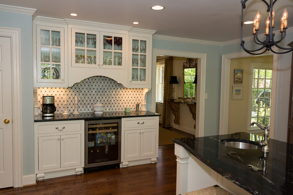 Inspiration for a mid-sized timeless single-wall medium tone wood floor kitchen remodel in Raleigh with white cabinets, granite countertops, stainless steel appliances, an island, an undermount sink, shaker cabinets, multicolored backsplash and mosaic tile backsplash