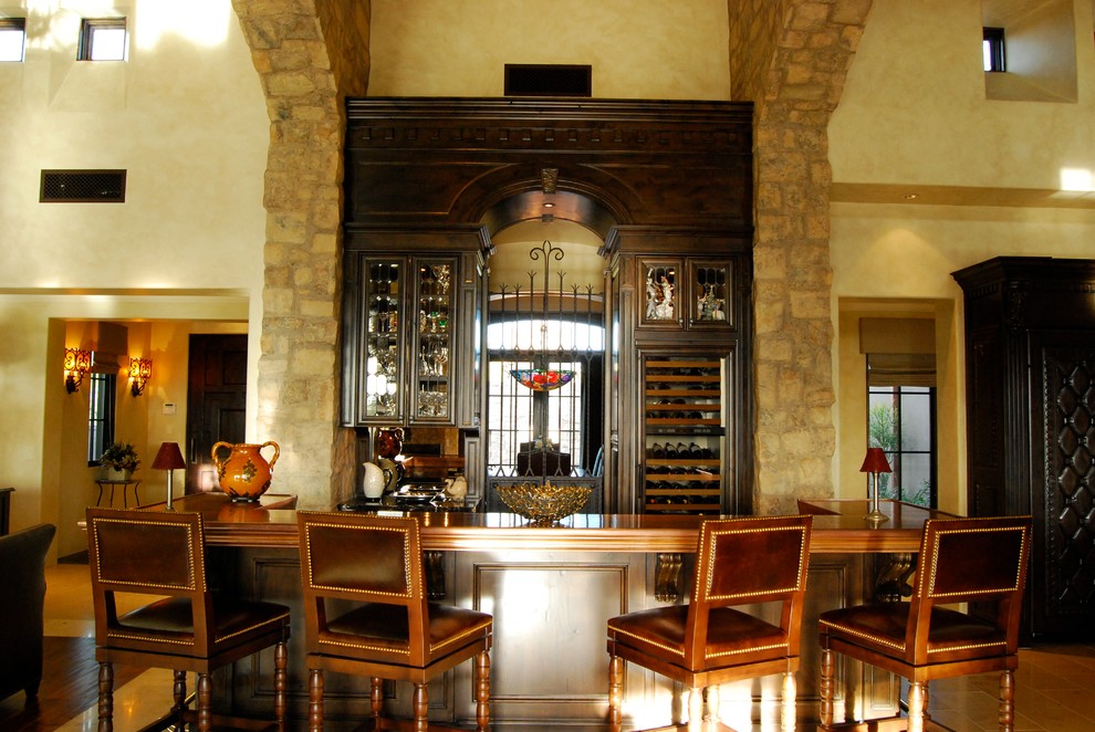 Exemple d'un très grand bar de salon linéaire chic en bois foncé avec des tabourets, un placard avec porte à panneau encastré, un plan de travail en bois et une crédence miroir.