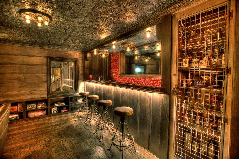 Foto di un bancone bar stile rurale di medie dimensioni con ante con riquadro incassato, ante marroni, top in legno, paraspruzzi rosso e pavimento in legno massello medio
