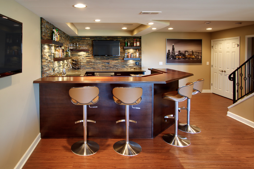 Large trendy medium tone wood floor seated home bar photo in Chicago with dark wood cabinets, wood countertops, multicolored backsplash, stone tile backsplash, brown countertops and open cabinets