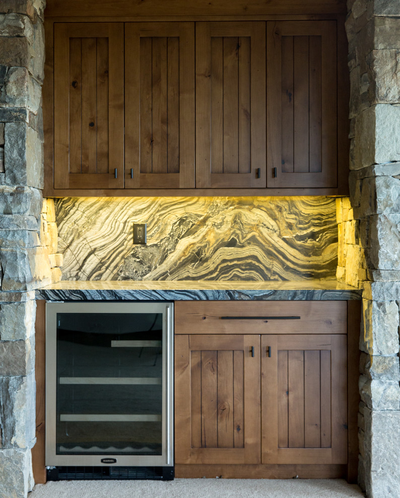 Exemple d'un bar de salon avec évier linéaire chic en bois brun de taille moyenne avec un placard à porte plane, un plan de travail en granite, une crédence en dalle de pierre et moquette.