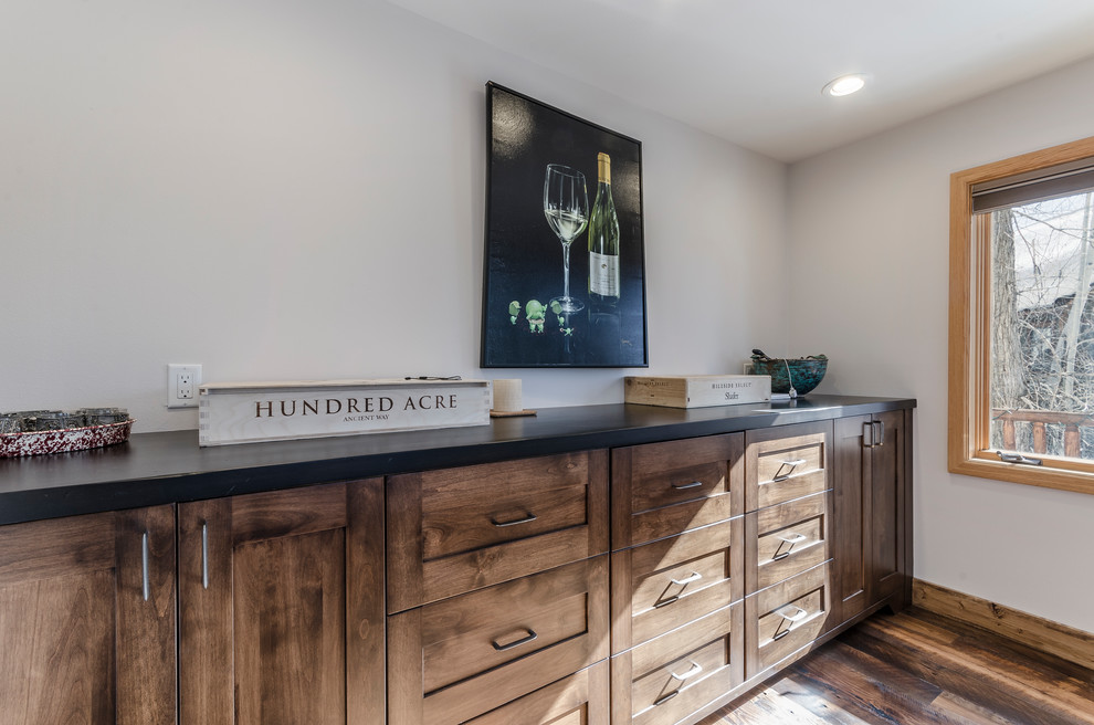 Rustikale Hausbar mit Schrankfronten im Shaker-Stil, dunklen Holzschränken, Küchenrückwand in Schwarz und braunem Holzboden in Denver