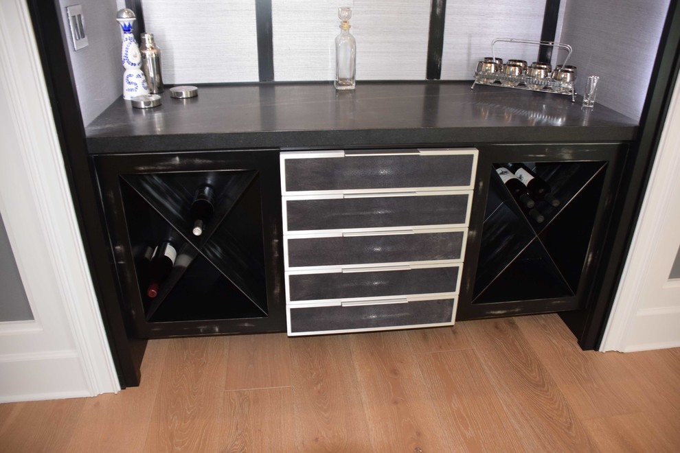 Modelo de bar en casa lineal minimalista de tamaño medio con armarios con paneles lisos, puertas de armario negras, encimera de granito y suelo de madera clara
