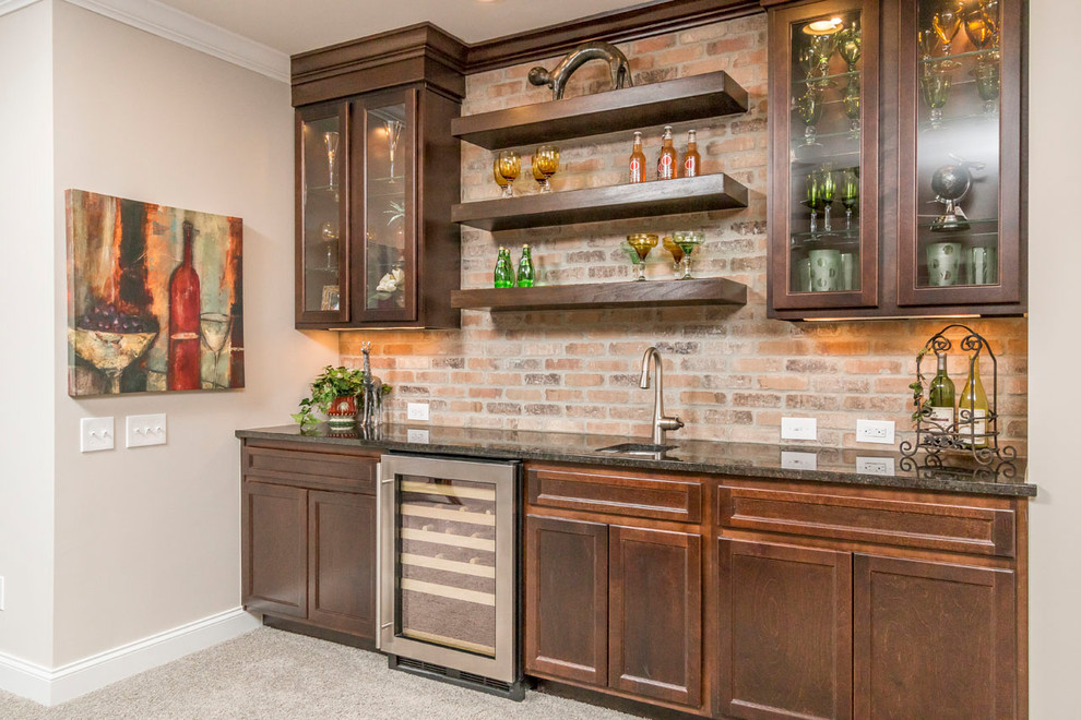 Photo of a medium sized classic single-wall wet bar in Columbus with a submerged sink, shaker cabinets, medium wood cabinets, granite worktops, brown splashback, brick splashback, carpet and brown floors.