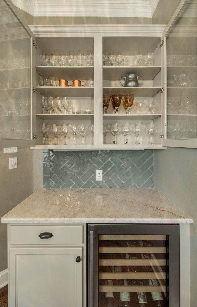Photo of a medium sized classic l-shaped home bar in Dallas with white cabinets, granite worktops, blue splashback, glass tiled splashback, glass-front cabinets and medium hardwood flooring.