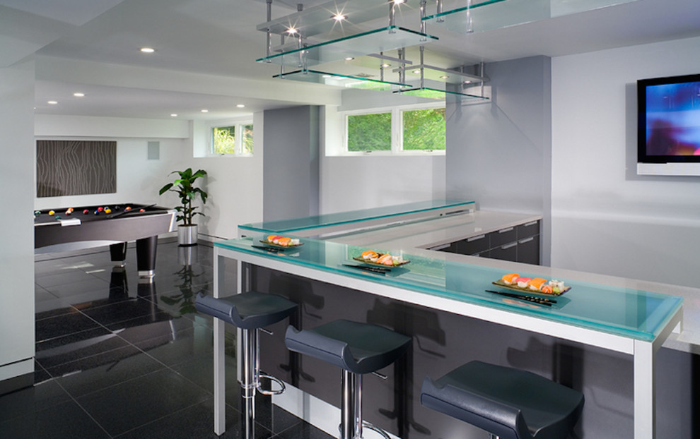 Inspiration for a large modern l-shaped breakfast bar in New York with flat-panel cabinets, grey cabinets, glass worktops, grey splashback and ceramic flooring.
