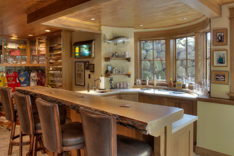 Aménagement d'un bar de salon montagne en U et bois brun avec des tabourets, un placard à porte shaker et un plan de travail blanc.