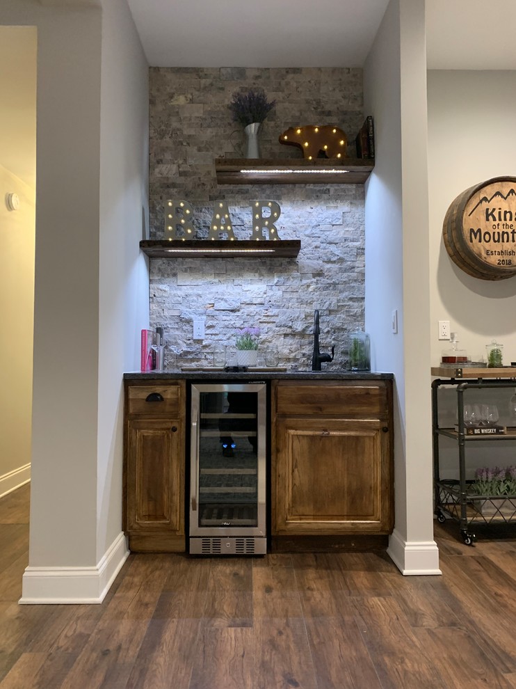 Cette image montre un bar de salon avec évier linéaire chalet en bois vieilli de taille moyenne avec un plan de travail en granite, une crédence en carrelage de pierre, sol en stratifié et un sol marron.