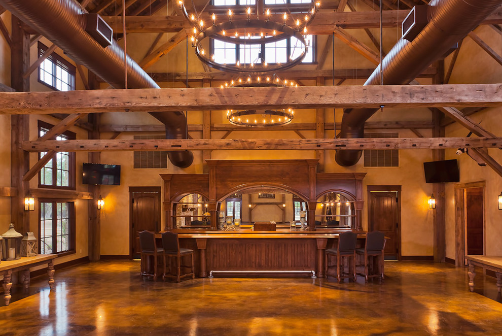 Cette photo montre un très grand bar de salon parallèle chic en bois brun avec des tabourets, un plan de travail en bois et sol en béton ciré.
