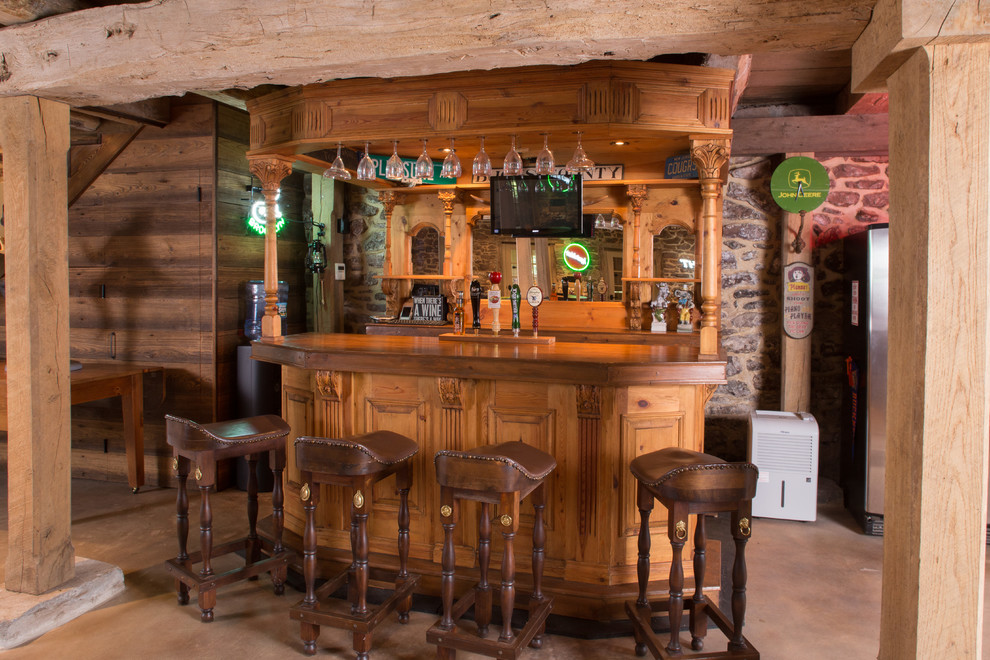На фото: параллельный домашний бар в стиле кантри с бетонным полом, барной стойкой, фасадами цвета дерева среднего тона, деревянной столешницей и коричневой столешницей