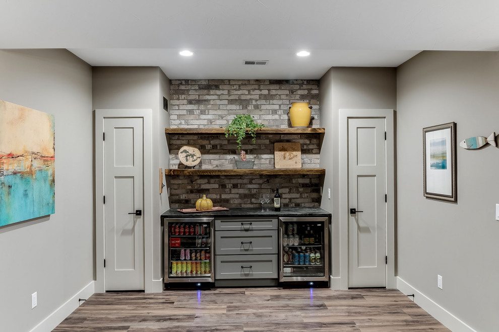 This is an example of a medium sized classic single-wall home bar in Other with no sink, shaker cabinets, grey cabinets, grey splashback, brick splashback, red floors and black worktops.