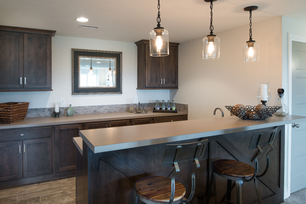 Example of a mid-sized cottage single-wall medium tone wood floor wet bar design in Wichita with shaker cabinets, dark wood cabinets, solid surface countertops and mosaic tile backsplash