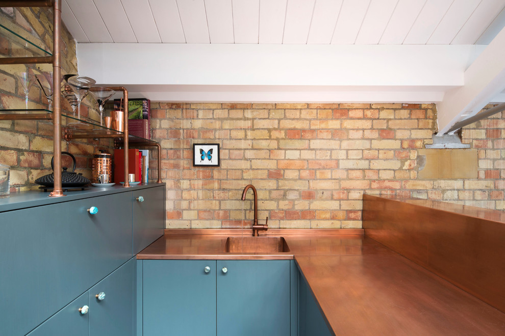 Small contemporary u-shaped wet bar in London with a built-in sink, flat-panel cabinets, dark wood cabinets, copper worktops, brown splashback, brick splashback, painted wood flooring, blue floors and brown worktops.