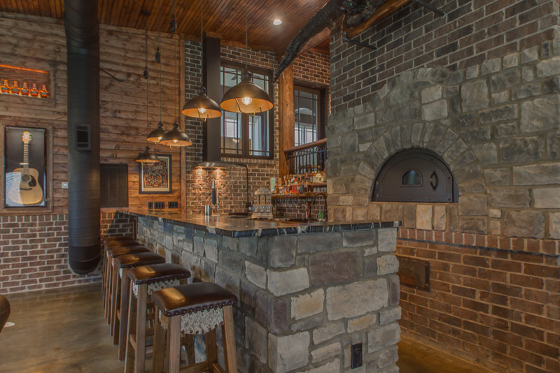 Modelo de bar en casa rústico grande con encimera de granito y suelo de cemento