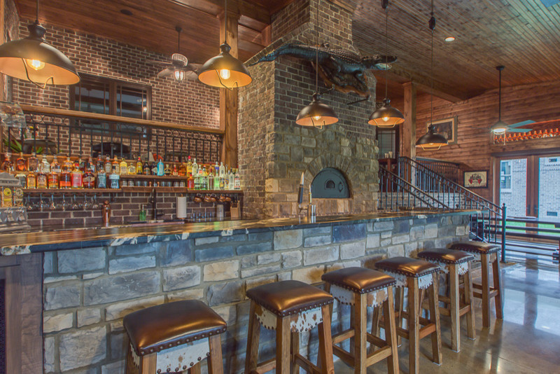Cette photo montre un grand bar de salon parallèle montagne avec des tabourets, un placard à porte shaker et sol en béton ciré.