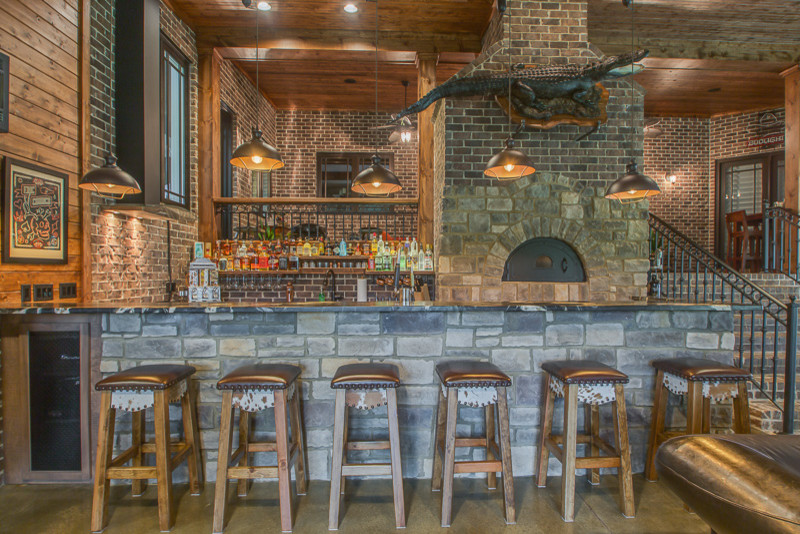 Foto di un grande bancone bar stile rurale con ante in stile shaker, ante marroni, top in granito e pavimento in cemento