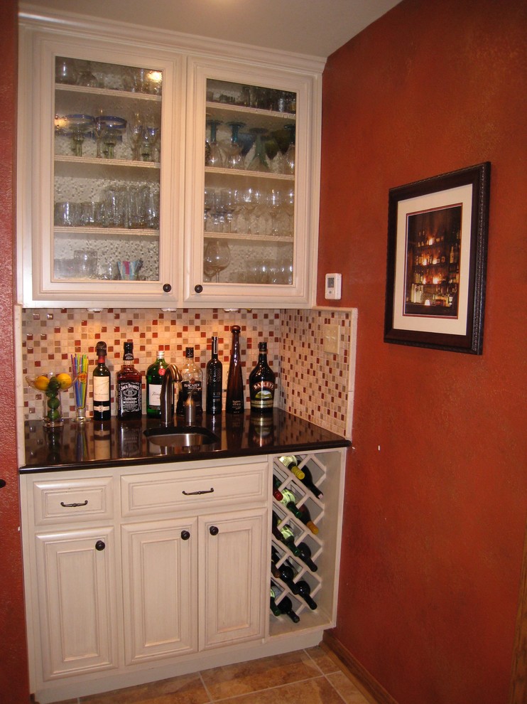 This is an example of a large classic l-shaped wet bar in Austin with a submerged sink, recessed-panel cabinets, engineered stone countertops, multi-coloured splashback, stone tiled splashback, porcelain flooring and beige cabinets.