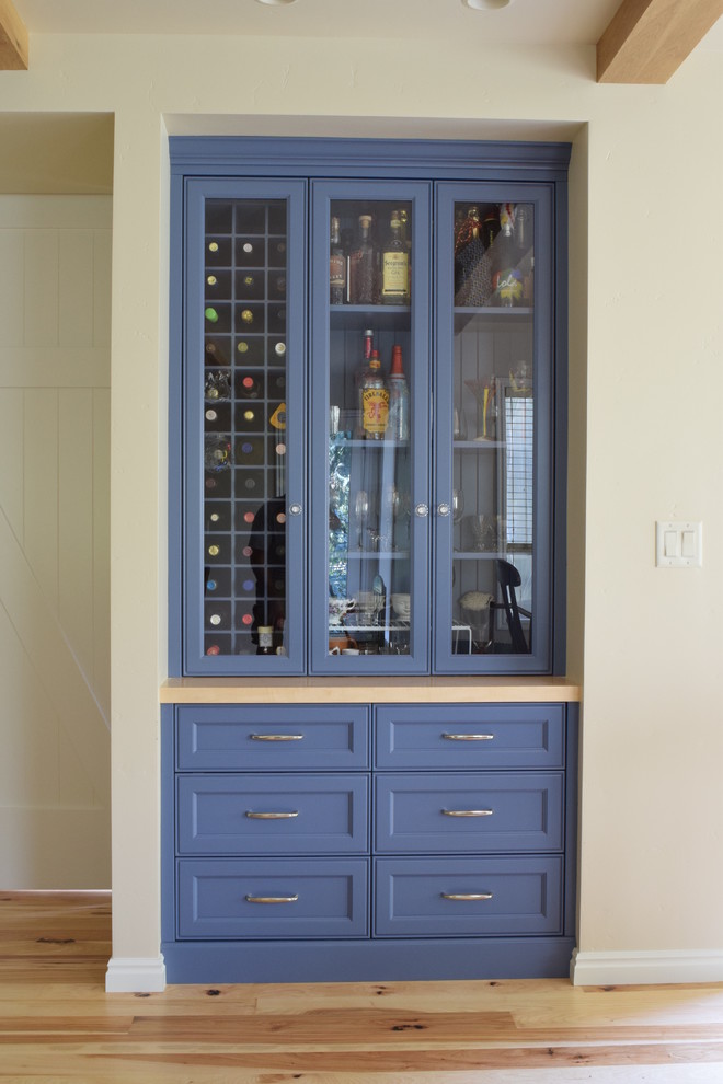 Cette image montre un bar de salon linéaire traditionnel de taille moyenne avec un placard à porte shaker, des portes de placard bleues, un plan de travail en surface solide et parquet clair.