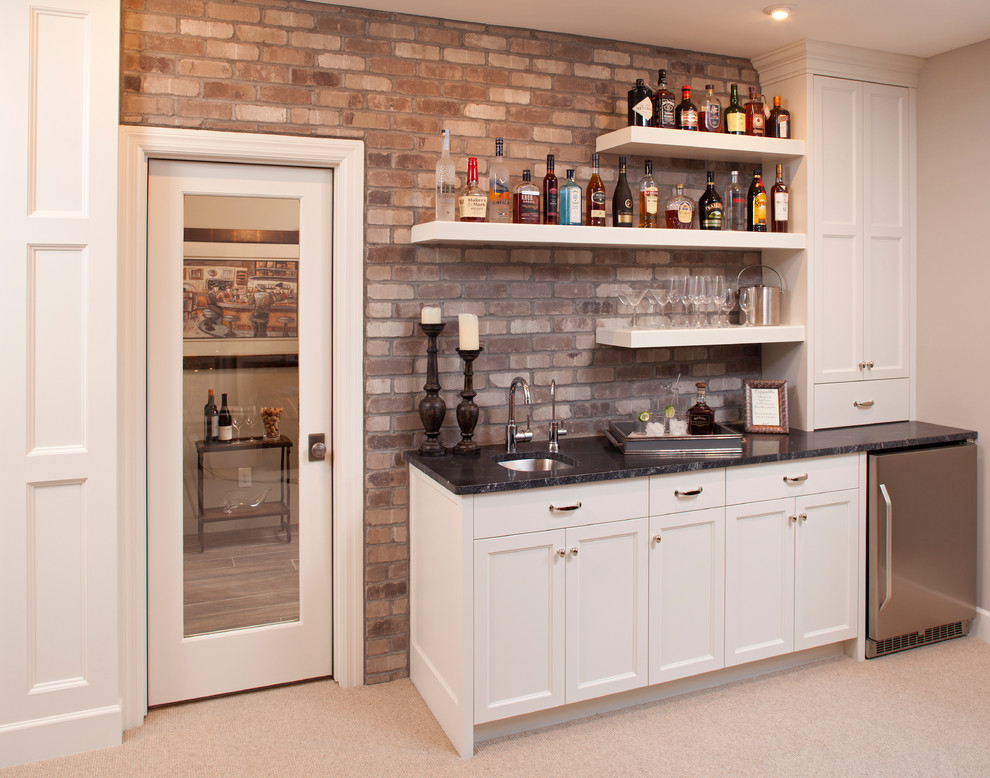 This is an example of a traditional single-wall wet bar in Minneapolis with carpet, a submerged sink, recessed-panel cabinets, white cabinets and beige floors.