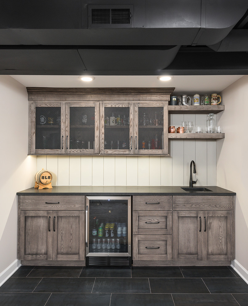 Inspiration for a mid-sized transitional single-wall black floor and slate floor wet bar remodel in Chicago with white backsplash, wood backsplash, black countertops, medium tone wood cabinets, an undermount sink, recessed-panel cabinets and soapstone countertops