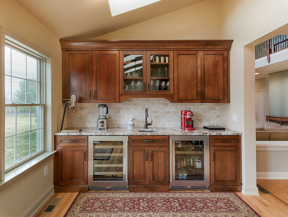 This is an example of a medium sized traditional wet bar in Philadelphia with beaded cabinets, a submerged sink, dark wood cabinets, granite worktops, light hardwood flooring, beige splashback and ceramic splashback.