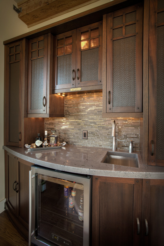 Photo of a medium sized traditional single-wall wet bar in Detroit with a submerged sink, shaker cabinets, dark wood cabinets, stainless steel worktops, beige splashback, matchstick tiled splashback and dark hardwood flooring.