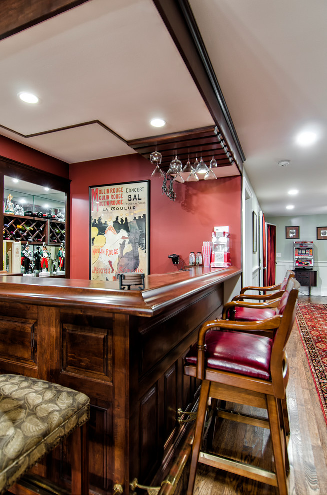 Aménagement d'un bar de salon classique en L et bois foncé de taille moyenne avec des tabourets, un évier encastré, un placard sans porte, un plan de travail en bois, une crédence rouge et un sol en bois brun.