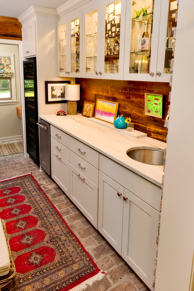 Wet bar - small transitional single-wall brick floor and multicolored floor wet bar idea in New Orleans with an undermount sink, glass-front cabinets, white cabinets, brown backsplash, wood backsplash and multicolored countertops