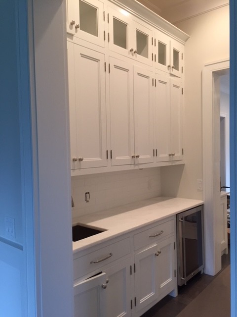 Medium sized traditional single-wall wet bar in New York with a submerged sink, recessed-panel cabinets, white cabinets, composite countertops, white splashback and metro tiled splashback.