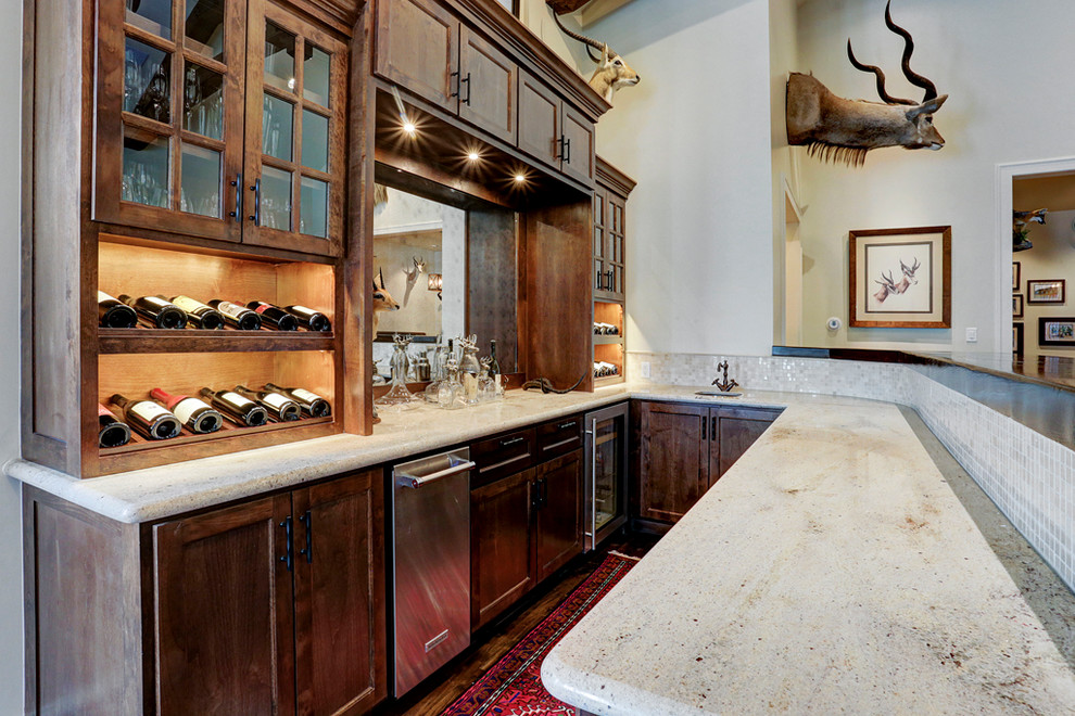 Elegant medium tone wood floor and brown floor seated home bar photo in Houston with an integrated sink, shaker cabinets, brown cabinets, marble countertops and multicolored countertops