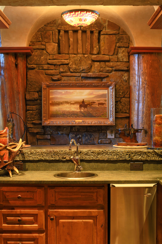 Foto di un angolo bar con lavandino stile rurale con lavello da incasso, ante con bugna sagomata, ante in legno scuro, top in saponaria e paraspruzzi in lastra di pietra
