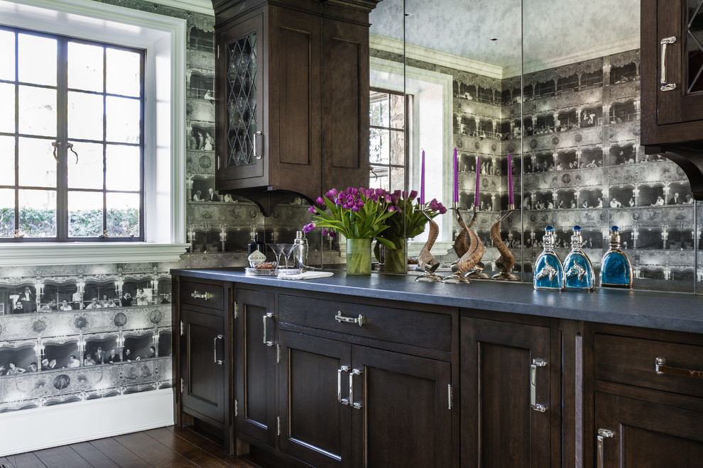 Klassische Hausbar mit Schrankfronten im Shaker-Stil, dunklen Holzschränken, Granit-Arbeitsplatte, Rückwand aus Spiegelfliesen und braunem Holzboden in New York