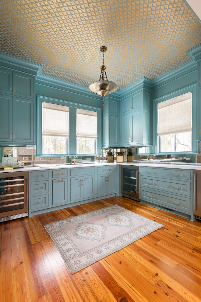Bild på en 50 tals vita vitt hemmabar med vask, med en nedsänkt diskho, luckor med profilerade fronter, blå skåp, bänkskiva i kvarts, spegel som stänkskydd, mörkt trägolv och brunt golv