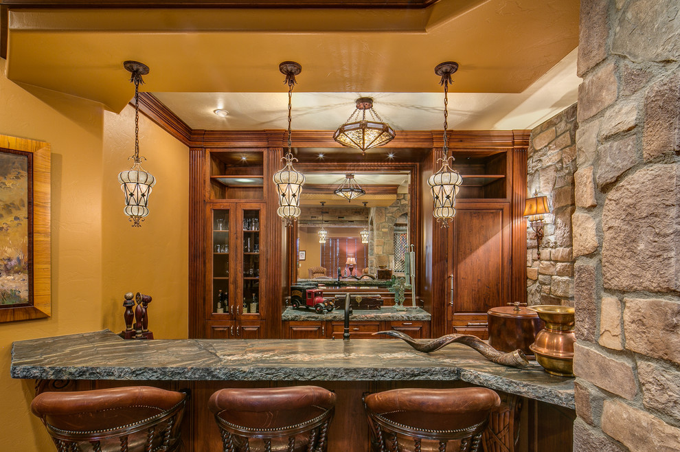Ejemplo de bar en casa con barra de bar de estilo americano con armarios tipo vitrina, puertas de armario de madera oscura y salpicadero con efecto espejo