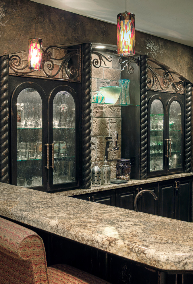 Immagine di un bancone bar rustico di medie dimensioni con ante con bugna sagomata, ante marroni, top in granito, paraspruzzi beige, paraspruzzi con piastrelle in pietra, pavimento in travertino e pavimento beige