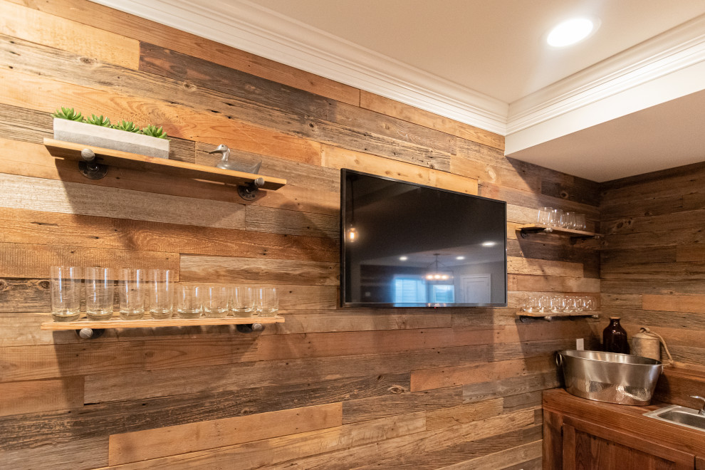 This is an example of a large rustic l-shaped wet bar in Philadelphia with a built-in sink, distressed cabinets, wood worktops, brown splashback, tonge and groove splashback, grey floors and brown worktops.