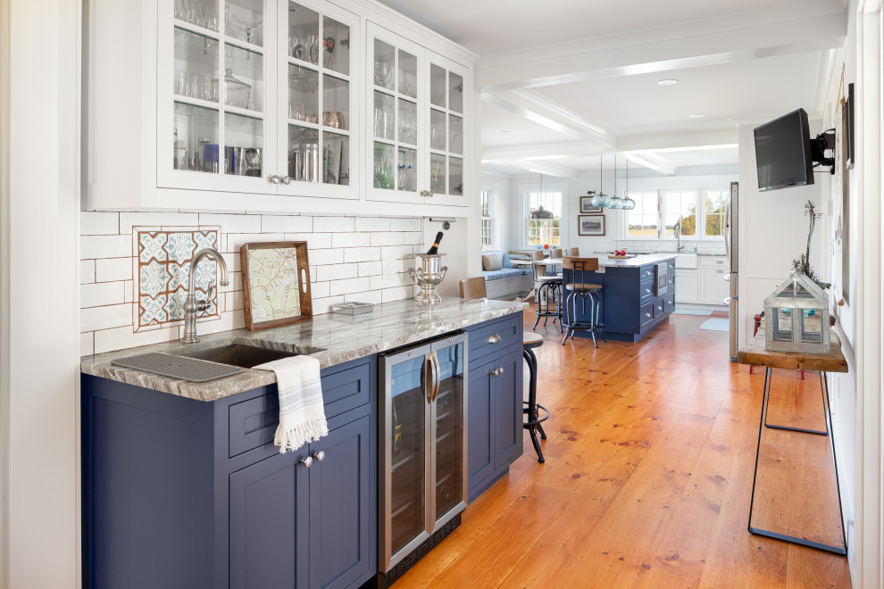 Mid-sized transitional single-wall medium tone wood floor and brown floor wet bar photo in Providence with an undermount sink, shaker cabinets, blue cabinets, white backsplash, subway tile backsplash and gray countertops