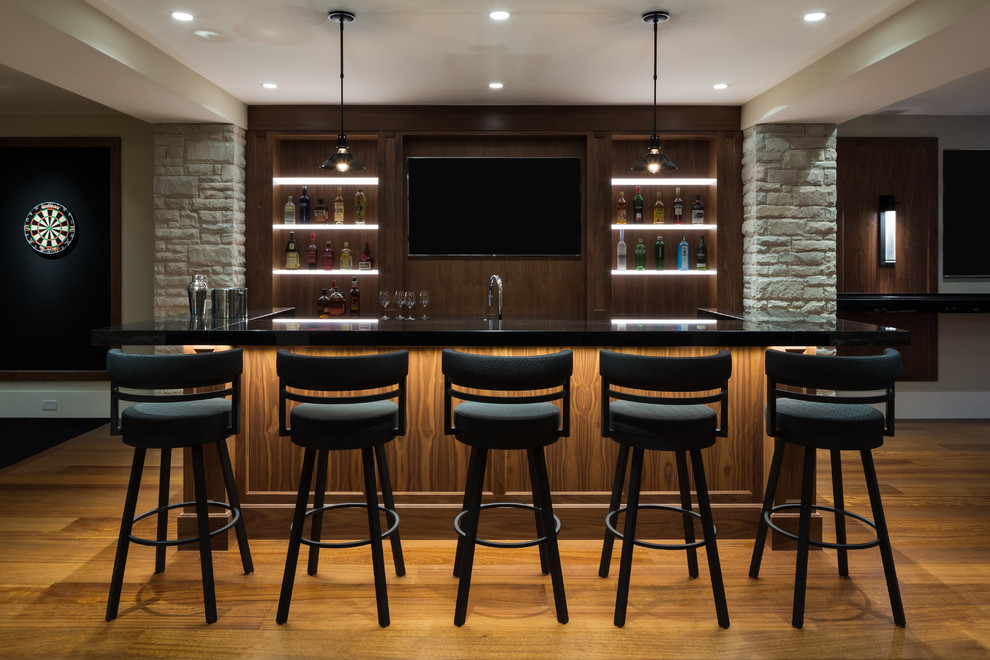 Cette photo montre un grand bar de salon parallèle tendance en bois brun avec des tabourets, un placard à porte shaker, un plan de travail en quartz modifié, une crédence marron, une crédence en bois, un sol en bois brun et un sol marron.